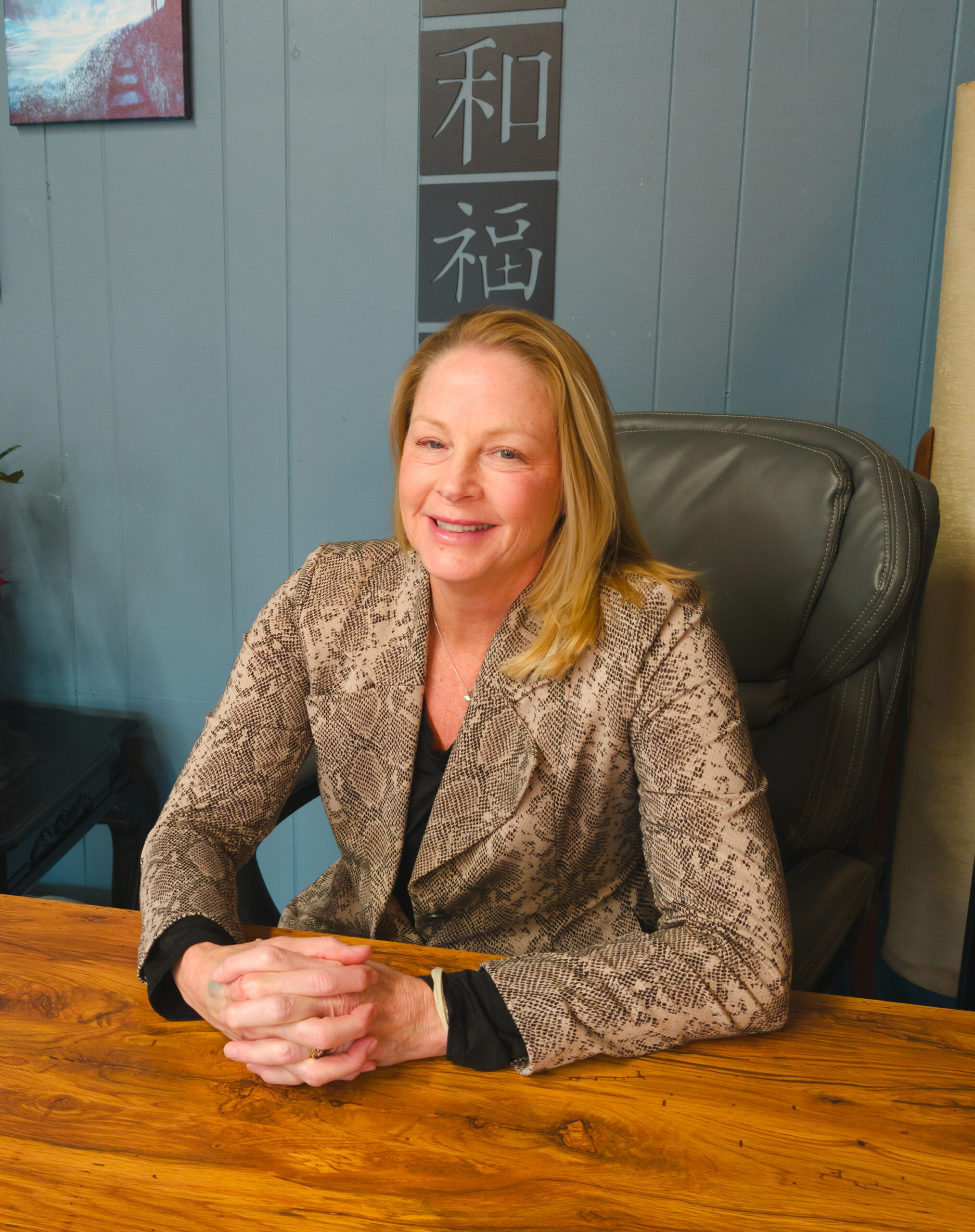 Acupuncturist Patty Kuchar sitting at her desk with her arms folded in front of her